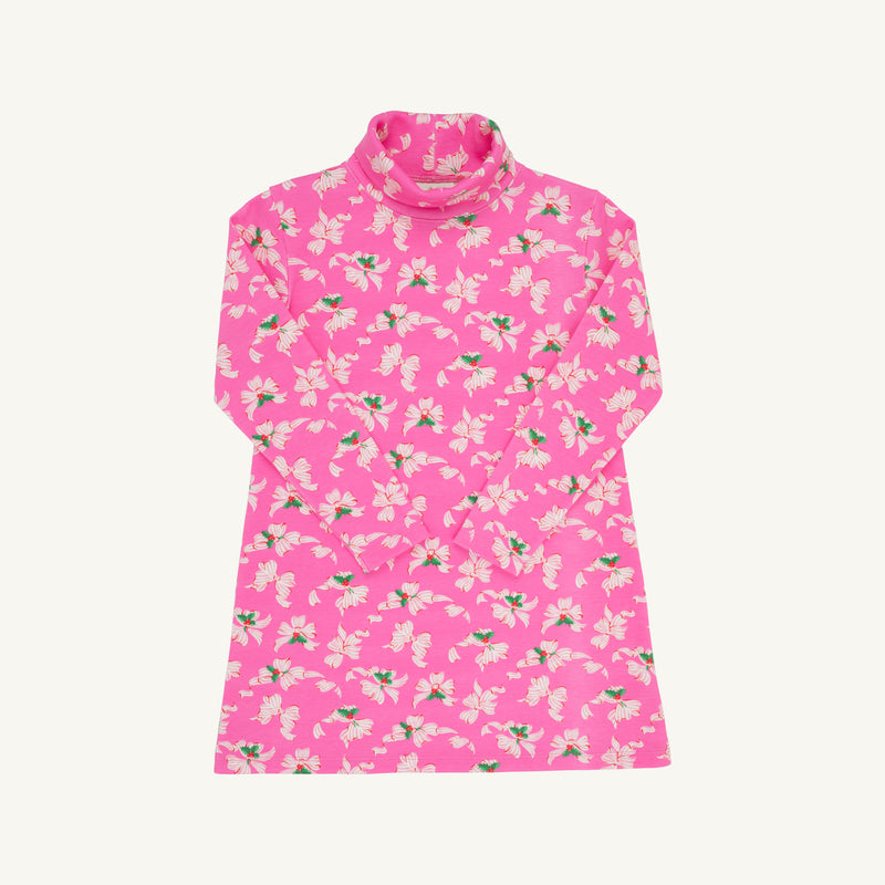Tatum’s Turtleneck Dress - Bows of Holly by The Beaufort Bonnet Company is a long-sleeved pink turtleneck dress made from soft Pima cotton, adorned with an all-over pattern of white and light pink flowers with green leaves. This holiday dress is shown laid flat against a white background.